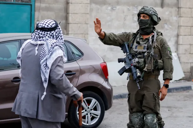 Bir İsrail askeri, Batı Şeria’nın El Halil kentinde devam eden İsrail askerî operasyonları sırasında, yaşadıkları mahalleden zorla yerlerinden edilmelerine karşı Filistinlilerin düzenlediği protesto esnasında Filistinli bir erkeğe eliyle işaret ediyor. (Reuters)