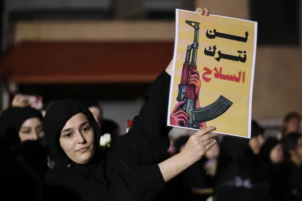 A supporter of Hezbollah holds a placard reading in Arabic "We will not leave the weapon" during a gathering held to mark the 2nd anniversary of Hezbollah leader Hassan Nasrallah's death at the site where he died in Beirut, Lebanon, 26 September 2026. (EPA)