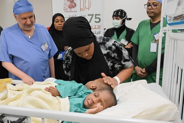 د. عبد الله الربيعة يطمئن على التوأم الملتصق التنزاني «لايتيينس ولوفنس» قبل بدء العملية (واس)