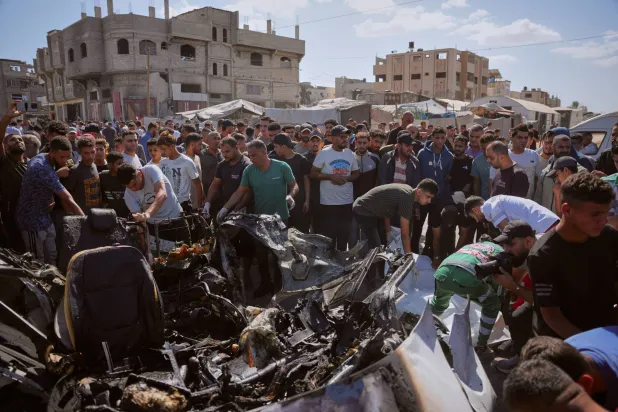 فلسطينيون يتفقدون حطام مركبة دُمرت في غارة جوية إسرائيلية بمخيم المغازي للاجئين وسط قطاع غزة 29 أكتوبر 2026 (أ.ب)