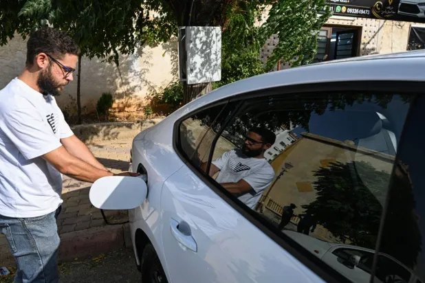 Ahmed Al-Lahham, a driver for ride-hailing application "Yalla Go!", charges his plug-in hybrid vehicle (PHEV) in Damascus. LOUAI BESHARA / AFP
