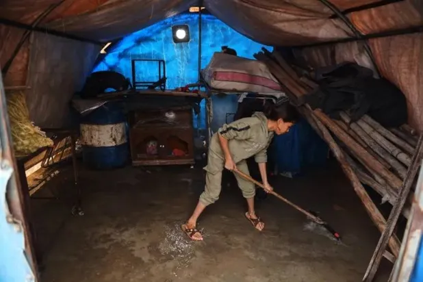 A displaced Syrian girl sweeps rainwater from the floor of her family's tent following a rainstorm at the al-Talae displacement camp in Hasakah, northeastern Syria, on October 29, 2026 [Baderkhan Ahmad/AP Photo]
