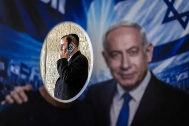 Kudüs'te, İsrail seçimlerinden önce parti ön seçimleri sırasında bir seçim merkezinde, Likud partisi üyesi, İsrail Başbakanı Binyamin Netanyahu'ya ait bir posterin arkasında duruyor(AFP)