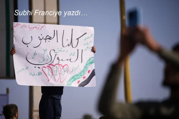 Suriye'nin Dera şehrinde, Kuneytra ve batı Dera bölgelerine yönelik İsrail askeri müdahalelerine karşı düzenlenen protestoda, bir gösterici Arapça olarak “Hepimiz Güney Suriye'yiz” yazılı pankart taşıyor, 23 Ekim 2026