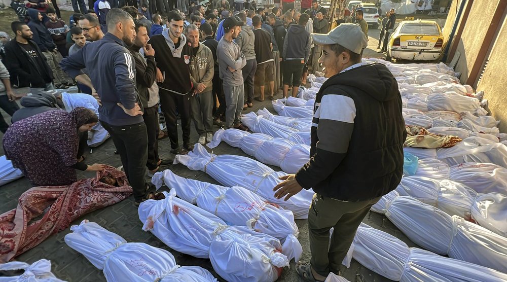 فلسطينيون يعاينون جثامين ضحايا القصف الإسرائيلي على مخيم جباليا أمام المستشفى الإندونيسي شمال قطاع غزة أمس (أ.ب)