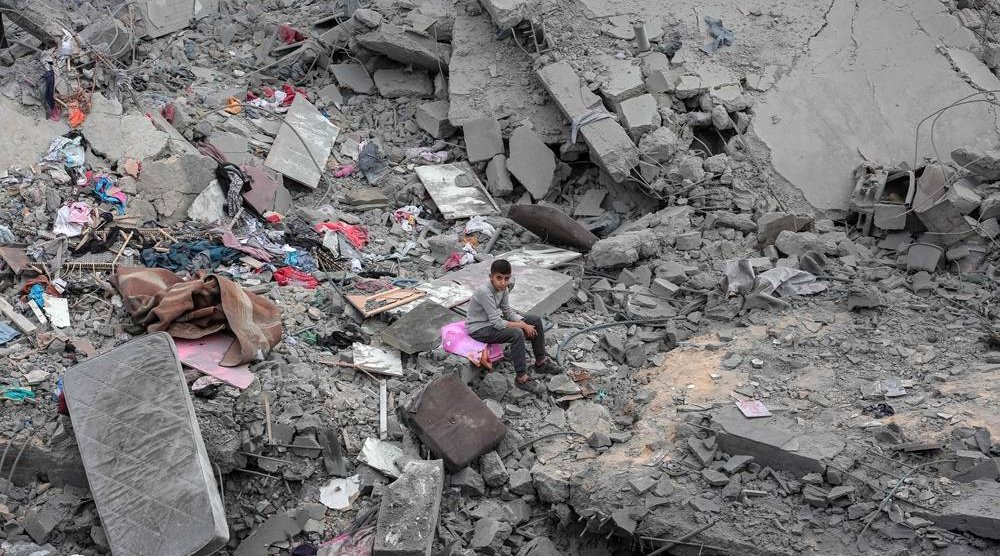 A boy sits among the rubble and scattered belongings of the Palestinian al-Atrash family, after their home was destroyed in an Israeli strike in Deir al-Balah in the central Gaza Strip on March 13, 2024, amid the ongoing conflict between Israel and the Hamas group. (AFP)