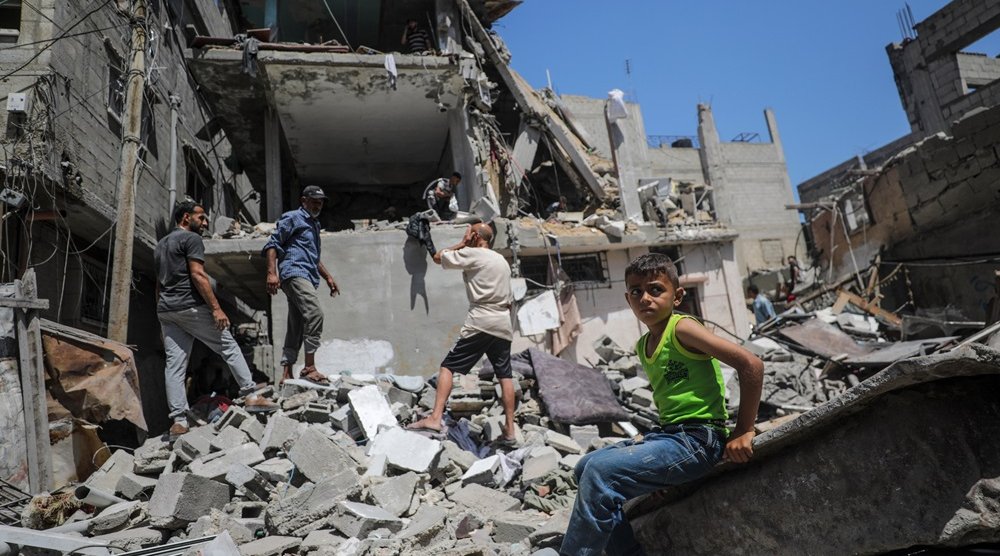 A child looks on as Palestinians search for missing people under the rubble of a destroyed house following an Israeli air strike, at al-Nuseirat refugee camp, southern Gaza Strip, 18 June 2024. (EPA) 