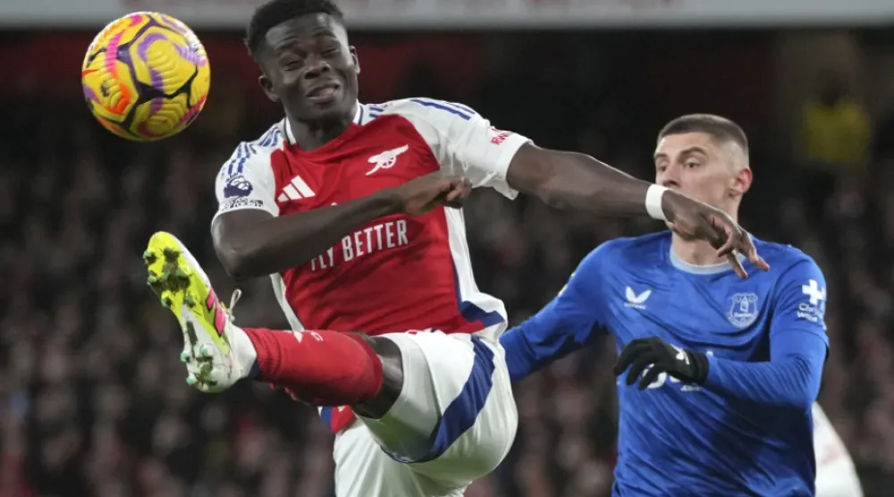Arsenal’s Bukayo Saka, left, kicks the ball ahead of Everton’s Vitaliy Mykolenko during the English Premier League soccer match between Arsenal and Everton at Emirates Stadium in London, Saturday, Dec. 14, 2024. (AP Photo/Kin Cheung)