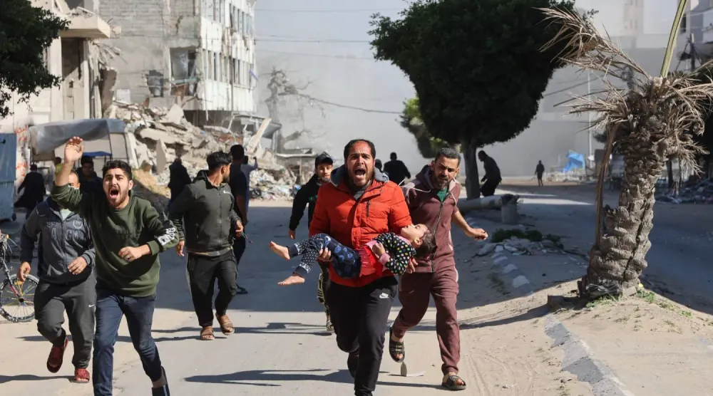 Bir Filistinli yaralı bir çocuğu Gazze Şeridi'nin merkezinde yerlerinden edilmiş insanların sığındığı ve dün İsrail saldırısına hedef olan bir bölgeden uzaklaştırıyor (AFP)