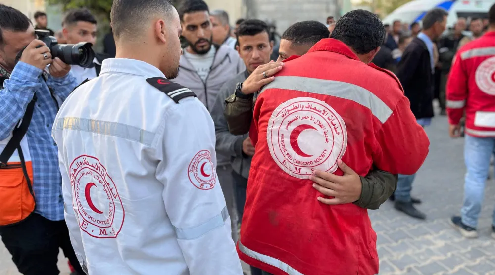 مسعف يعانق شاباً أثناء وصول جثامين المسعفين الفلسطينيين في خان يونس (أ.ف.ب)
