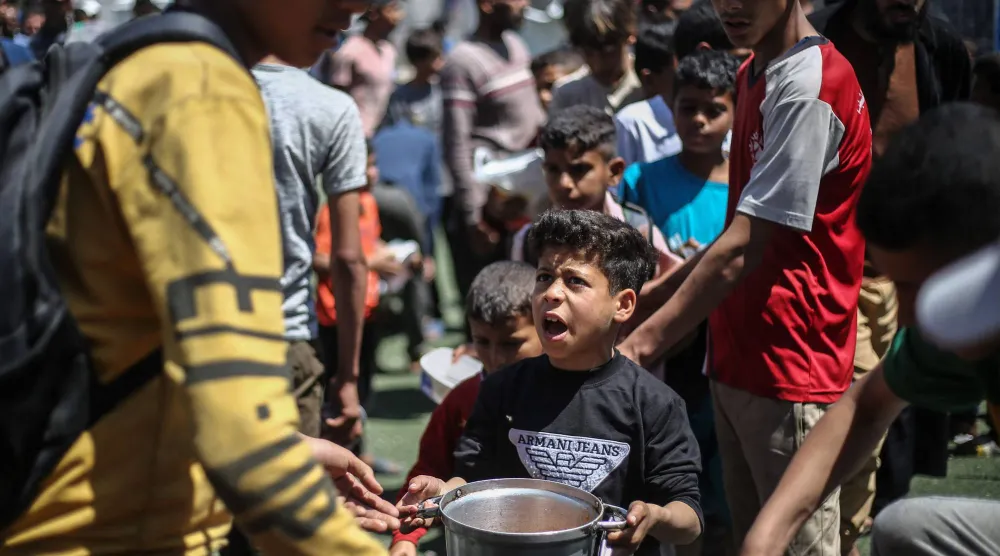 أطفال فلسطينيون خلال أخذ حصة من طعام في مخيم النصيرات للاجئين وسط قطاع غزة (أ.ف.ب)