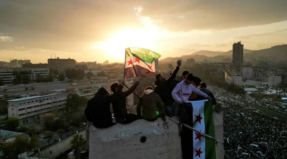 تُظهِر صورة التقطتها طائرة من دون طيار أشخاصاً يلوّحون بالأعلام خلال الاحتفالات في ساحة الأمويين 20 ديسمبر (رويترز)