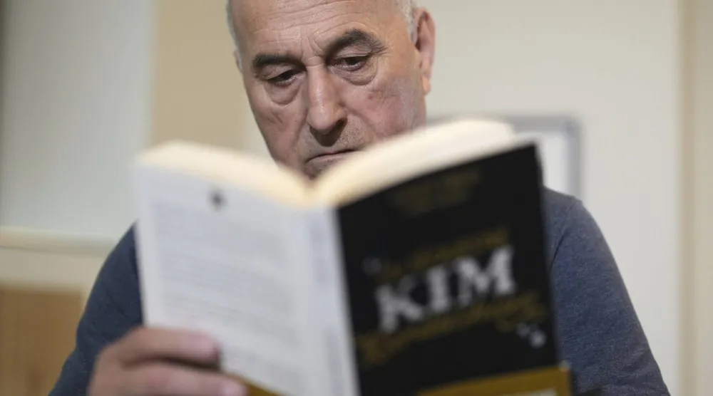 Yunice Abbas reads the book "I Sequestered Kim Kardashian" during an interview with the Associated Press, Tuesday, April 22, 2025 in Paris. (AP Photo/Thibault Camus)