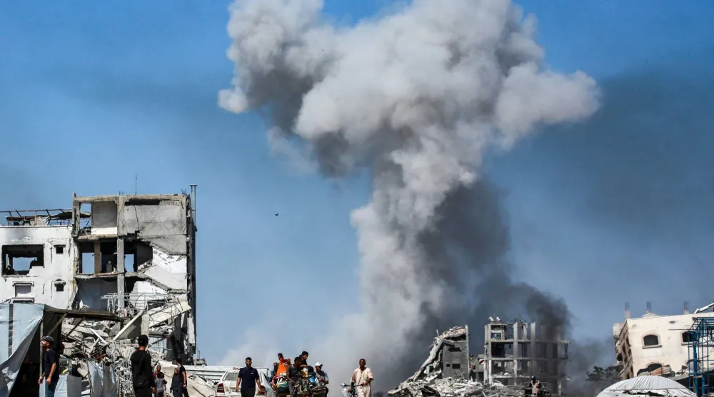 فلسطينيون يمرون وسط الدمار وأعمدة الدخان المتصاعد من القصف في جباليا بشمال قطاع غزة الأحد (أ.ف.ب)