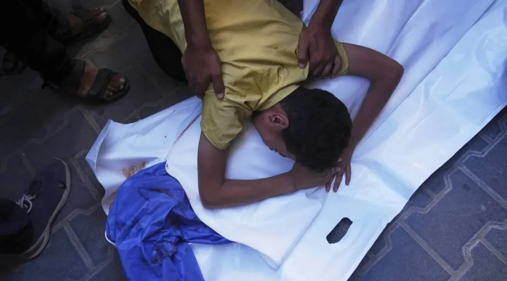 İsrail'in Nuseyrat'taki el-Avde Hastanesi'nin içme suyu dağıtım noktasına düzenlediği hava saldırısında hayatını kaybeden 12 yaşındaki arkadaşı Abdullah Ahmed'in yasını tutan Filistinli bir çocuk (AP)