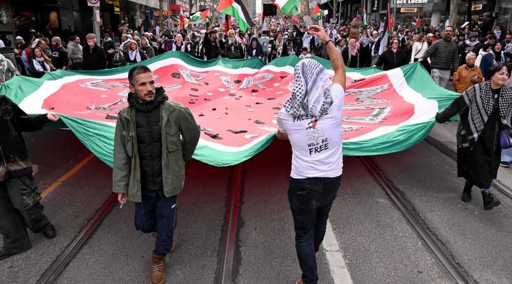 يحمل الناس لافتات ويلوحون بالأعلام خلال مسيرة مؤيدة للفلسطينيين في شوارع ملبورن يوم 6 يوليو 2025 (أ.ف.ب)