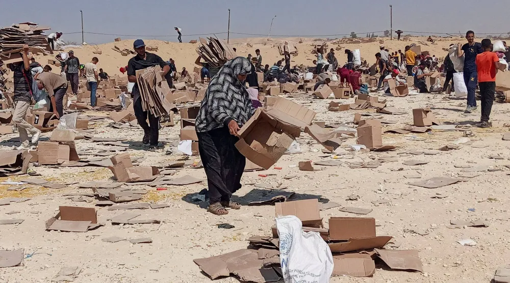فلسطينيون يجمعون بواقي مساعدات إنسانية في رفح بجنوب قطاع غزة (رويترز)