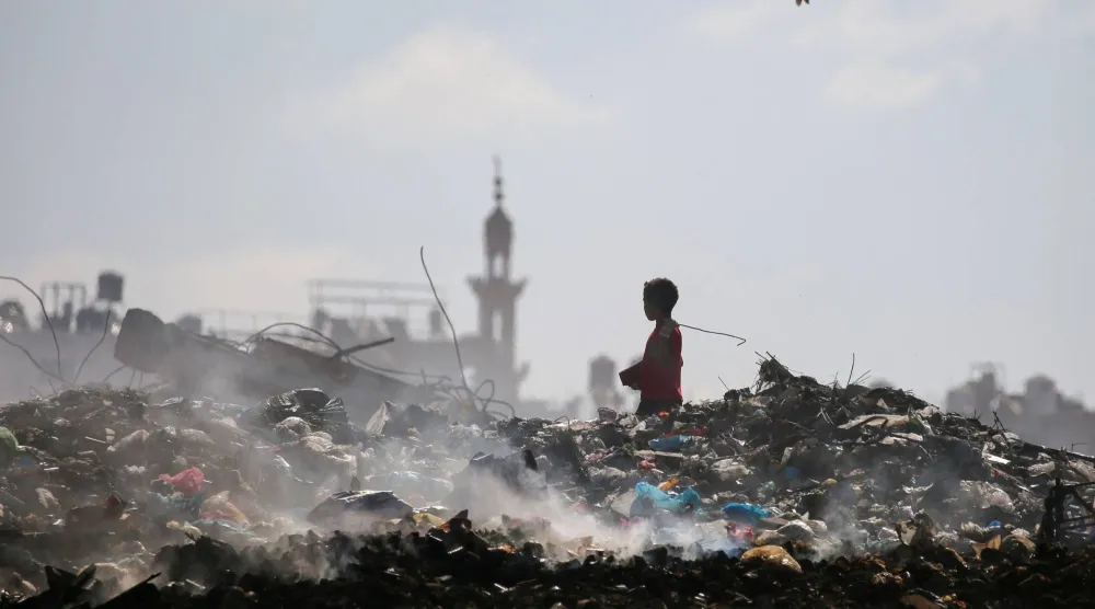 صبي فلسطيني يفتش بين النفايات في مخيم البريج وسط قطاع غزة يوم الاثنين (أ.ف.ب)