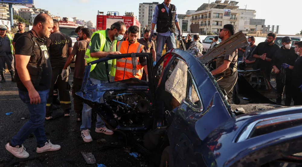 عناصر من الدفاع المدني يتجمعون بالقرب من سيارة استهدفتها غارة إسرائيلية في خلدة بلبنان (رويترز) 