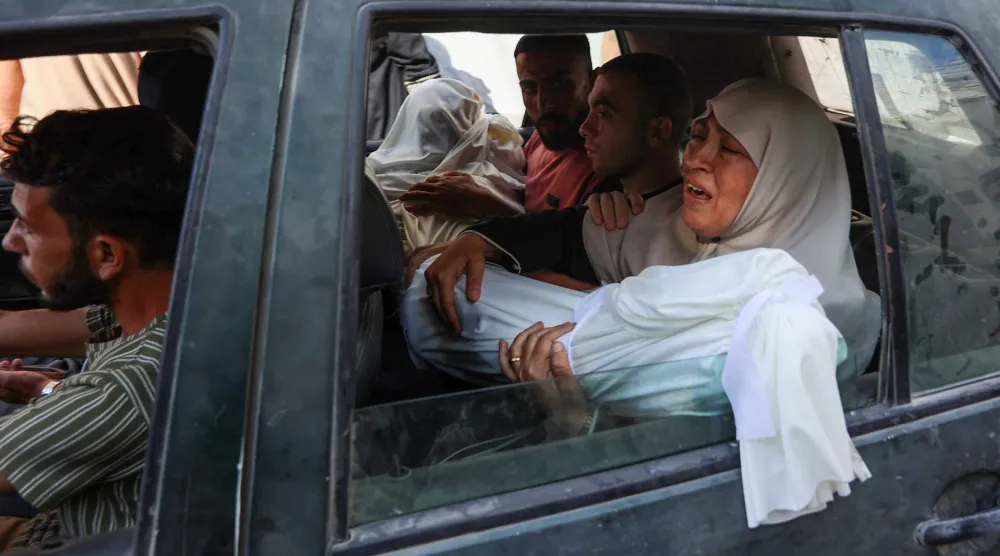 فلسطينية تحمل جثمان قريب لها قُتل بغارة إسرائيلية قبيل الجنازة في مدينة غزة أمس (أ.ف.ب)