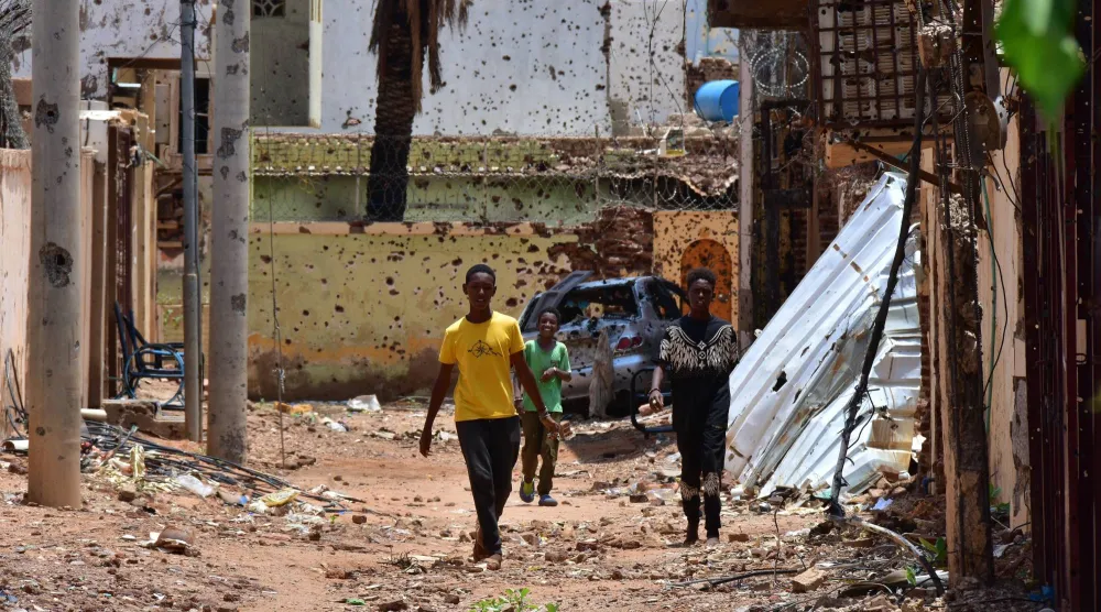 أشخاص يسيرون في شارع يحمل آثار الدمار نتيجة صراع دموي على السلطة في السودان (د.ب.أ)
