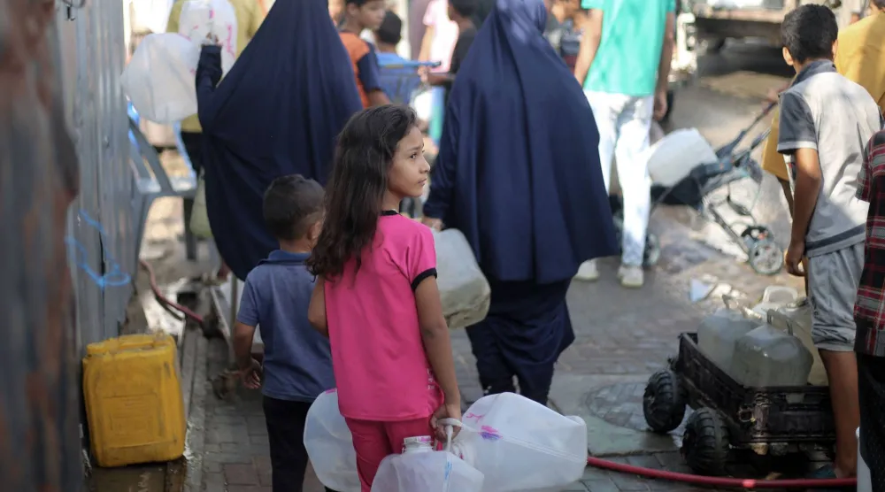 فلسطينيون يحصلون على المياه من نقطة توزيع بمخيم النصيرات للاجئين في وسط قطاع غزة (أ.ف.ب)