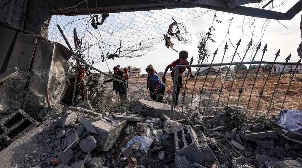 أطفال فلسطينيون يتفقدون أنقاض مبنى تضرر في غارة إسرائيلية على مخيم البريج للاجئين بوسط قطاع غزة (أ.ف.ب)