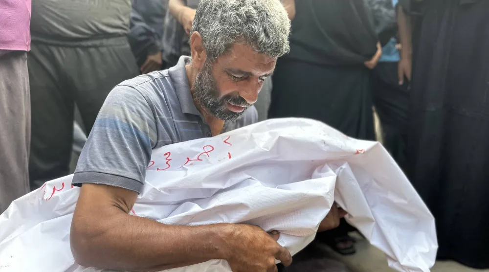 رجل يبكي على أحد أقاربه مع وصول جثث فلسطينيين قُتلوا في هجوم إسرائيلي على خيام إلى مستشفى النصر في خان يونس اليوم (د.ب.أ)