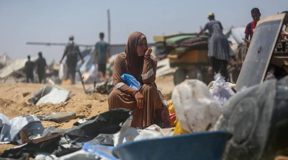 امرأة تجلس في الأنقاض وسط خيام مدمرة بمخيم مؤقت للنازحين في أعقاب توغل دبابات إسرائيلية جنوب قطاع غزة (أ.ف.ب)