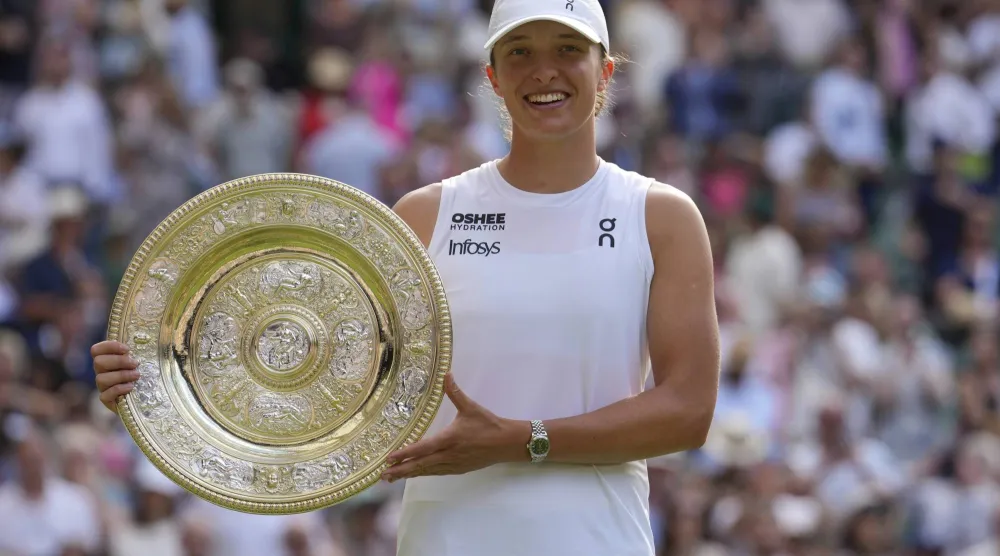 Poland's Iga Swiatek celebrates with the trophy after beating Amanda Anisimova of the US to win the women's singles final at the Wimbledon Tennis Championships in London, Saturday, July 12, 2025. (AP Photo/Kin Cheung)