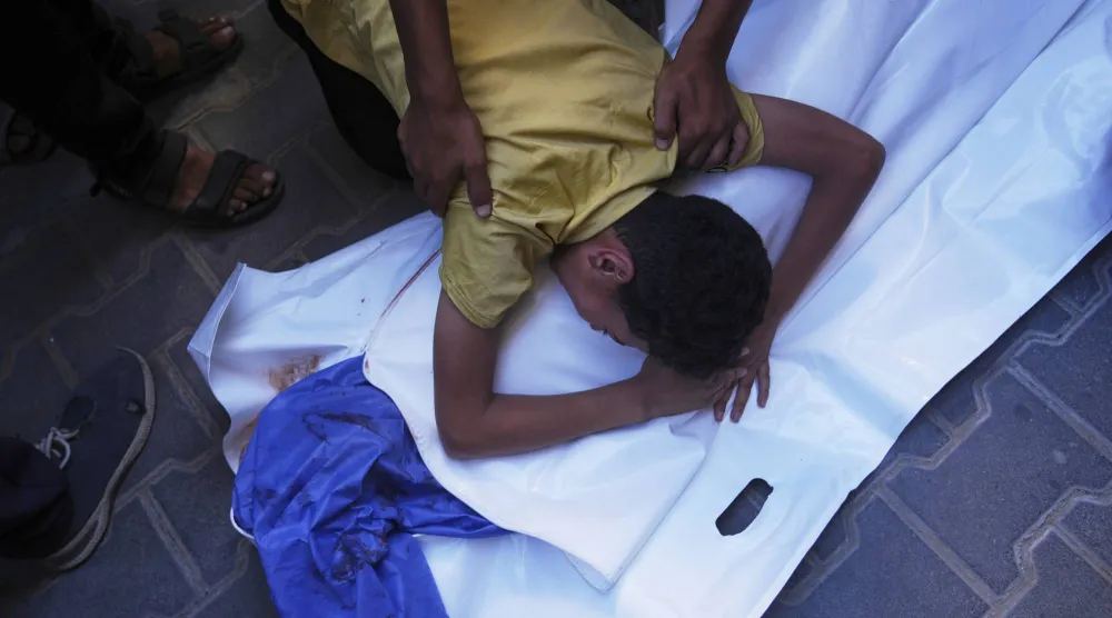 طفل فلسطيني ينعى جثمان صديقه عبد الله أحمد البالغ من العمر 12 عاماً والذي قُتل في غارة إسرائيلية استهدفت نقطة توزيع مياه الشرب بمستشفى العودة في النصيرات (أ.ب)