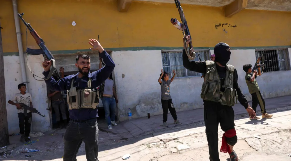 أفراد من قوات الأمن السورية وأطفال يحملون بنادق في أحد أحياء السويداء 15 يوليو 2025 (أ.ف.ب)