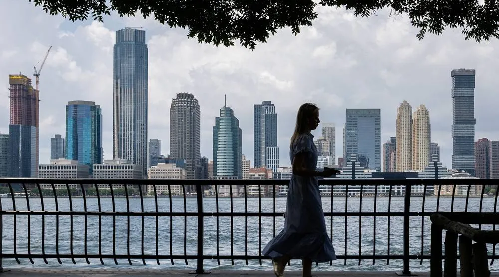  A woman walks along the Hudson River, with the Jersey City skyline in the background, in New York City, US, July 14, 2025. (Reuters)