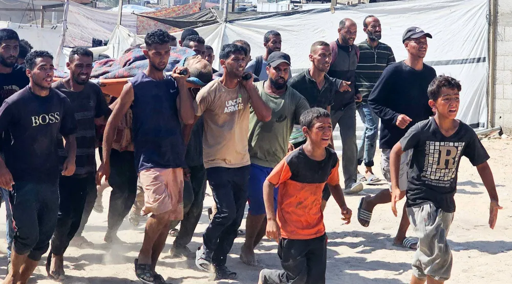 فلسطينيون ينقلون ضحايا إلى عيادة تابعة للصليب الأحمر برفح جنوب قطاع غزة بعد أن ورد أنهم تعرضوا لإطلاق نار أثناء انتظارهم لتلقّي طرود غذائية في نقطة توزيع تديرها مؤسسة غزة الإنسانية الأسبوع الماضي (أ.ف.ب)