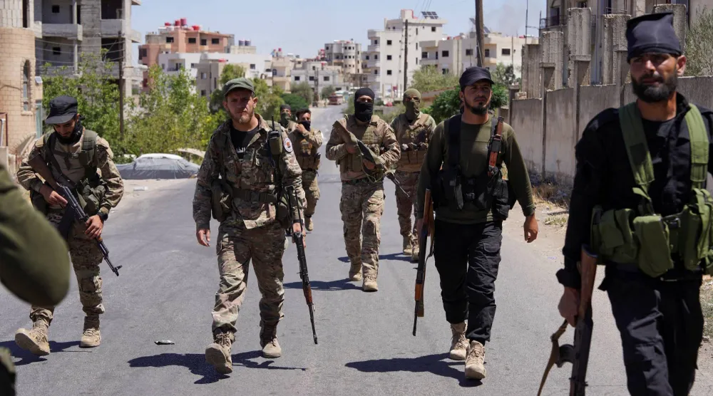 Syrian security forces walk together along a street, after clashes between Syrian government troops and local Druze fighters resumed in the southern Druze city of Sweida early on Wednesday, collapsing a ceasefire announced just hours earlier that aimed to put an end to days of deadly sectarian bloodshed, in Sweida, Syria July 16, 2025. REUTERS/Karam al-Masri