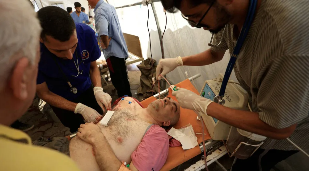 رجل فلسطيني مصاب يتلقى الرعاية الطبية بمستشفى الأهلي العربي بعد غارة إسرائيلية على كنيسة العائلة المقدسة (رويترز)