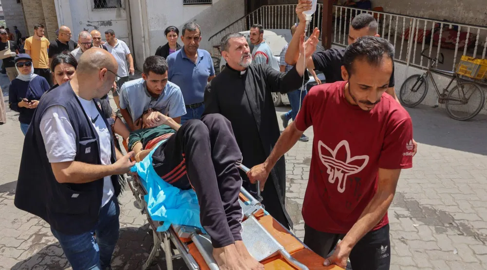 فلسطينيون ينقلون جريحاً أُصيب بغارة إسرائيلية على الكنيسة في غزة الخميس (أ.ف.ب)