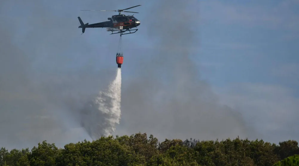 An Airbus H125 helicopter drops water over a wildfire in Saint-Julien Les Martigues, northwest of Marseille in southern France on July 18, 2025. (Photo by Christophe SIMON / AFP)