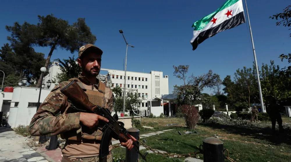 العلم السوري مرفوعاً أمام مبنى وزارة الدفاع في دمشق بعدما تعرض لأضرار بالغة جراء غارات جوية إسرائيلية يوم الأربعاء الماضي (أ.ب)