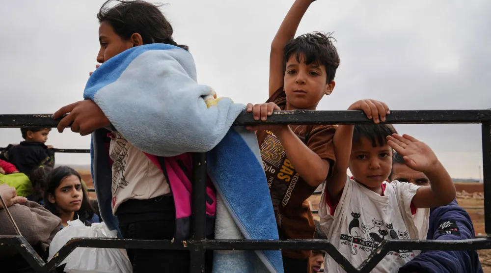 Syrian Bedouin families gesture as they ride in a convoy led by Red Crescent vehicles in Busra al-Harir, heading to Daraa after being evacuated from Sweida following more than a week of violent clashes, Monday, July 21, 2025. (AP Photo/Malek Khattab)