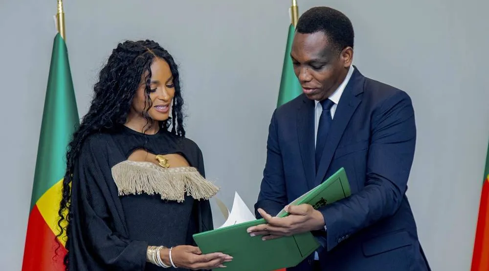  Yvon Detchenou, Benin's Minister of Justice and Legislation, right, presents citizenship documents to singer Ciara at a ceremony in Cotonou, Benin, Saturday July 26, 2025. (Benin Presidency via AP) 