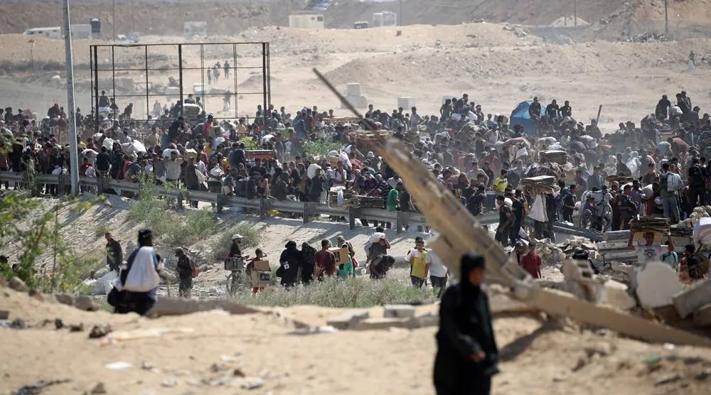 Palestinians return with bags, boxes and wooden pallets from a food distribution point run by the US and Israeli-backed Gaza Humanitarian Foundation (GHF) group, near the Netsarim corridor in the central Gaza Strip on August 3, 2025. (AFP)