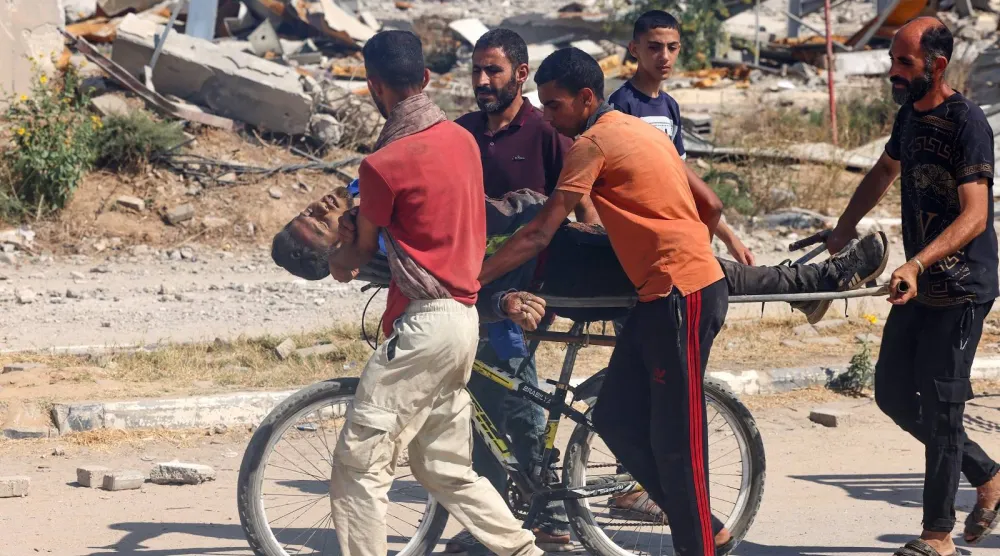 ​فلسطينيون يحملون شخصاً مصاباً على دراجة هوائية في شارع صلاح الدين بالنصيرات وسط قطاع غزة (أ.ف.ب)
