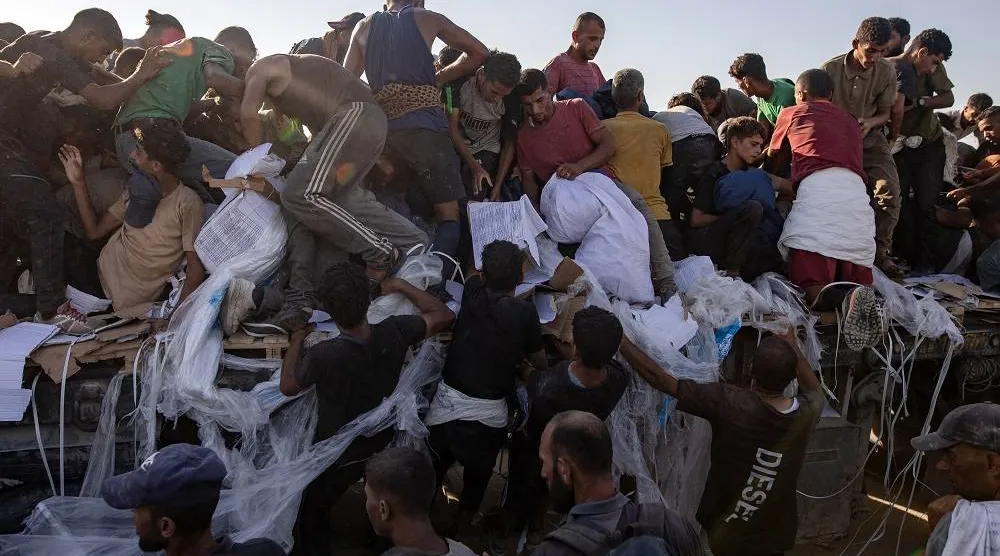 Internally displaced Palestinians climb aid trucks to get food near a food distribution point in the Morag corridor, south of Khan Younis, in the southern Gaza Strip, 04 August 2025. (EPA)
