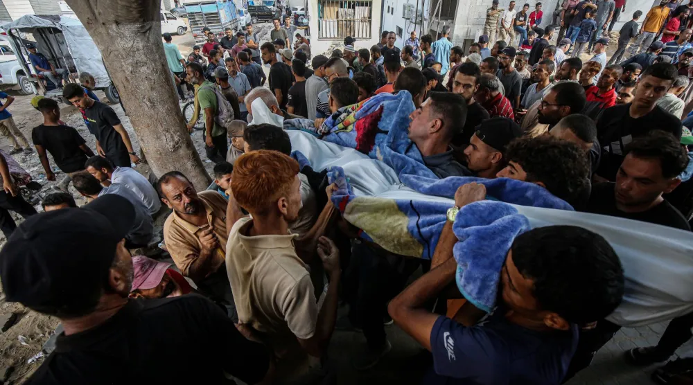 أشخاص يحملون جثث فلسطينيين قُتلوا بنيران إسرائيلية خلال محاولتهم تلقي المساعدات وفقاً للمسعفين في مستشفى «الشفاء»... (د.ب.أ)