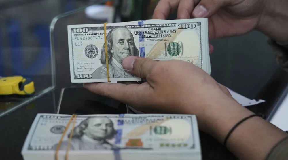 موظف يعدّ أوراق الدولار الأميركي في مكتب صرافة بجاكرتا، إندونيسيا (رويترز)