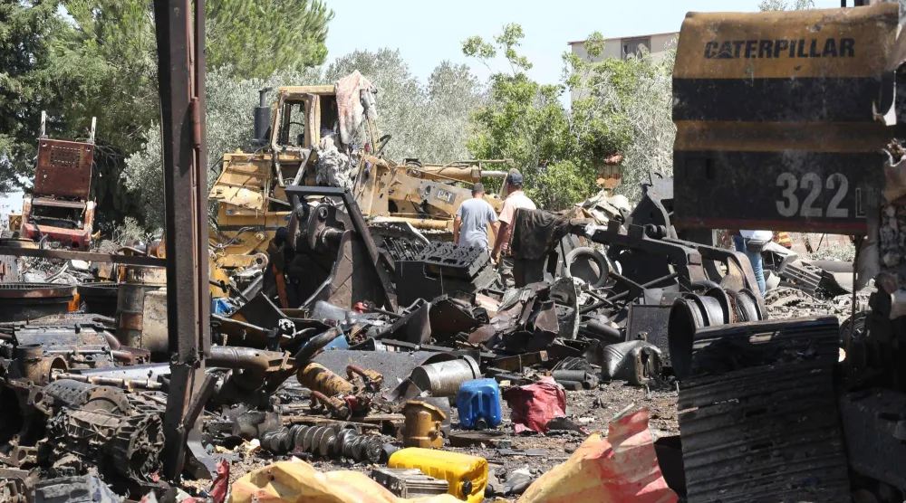 لبنانيون يتفقدون أمس آثار دمار خلفته غارة إسرائيلية ليلية على قرية دير سريان جنوب لبنان (أ.ف.ب)