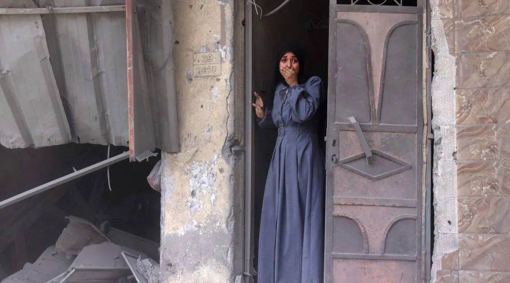 فلسطينية تقف على باب منزلها تعاين متأثرة أثار ضربة إسرائيلية في مدينة غزة أمس (أ.ف.ب)