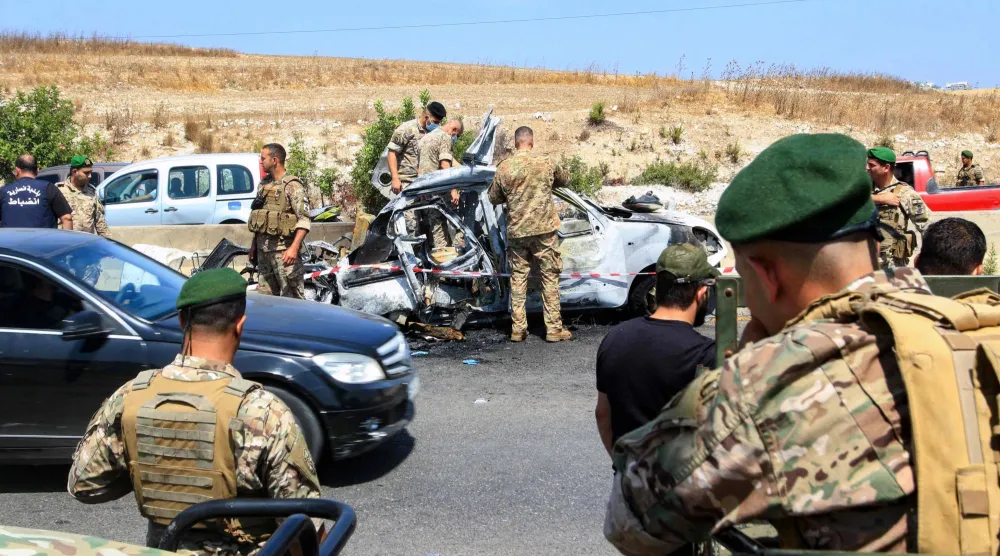 جنود لبنانيون يتفقدون حطام سيارة تعرضت لقصف إسرائيلي في جنوب مدينة صيدا الساحلية (أ.ف.ب)