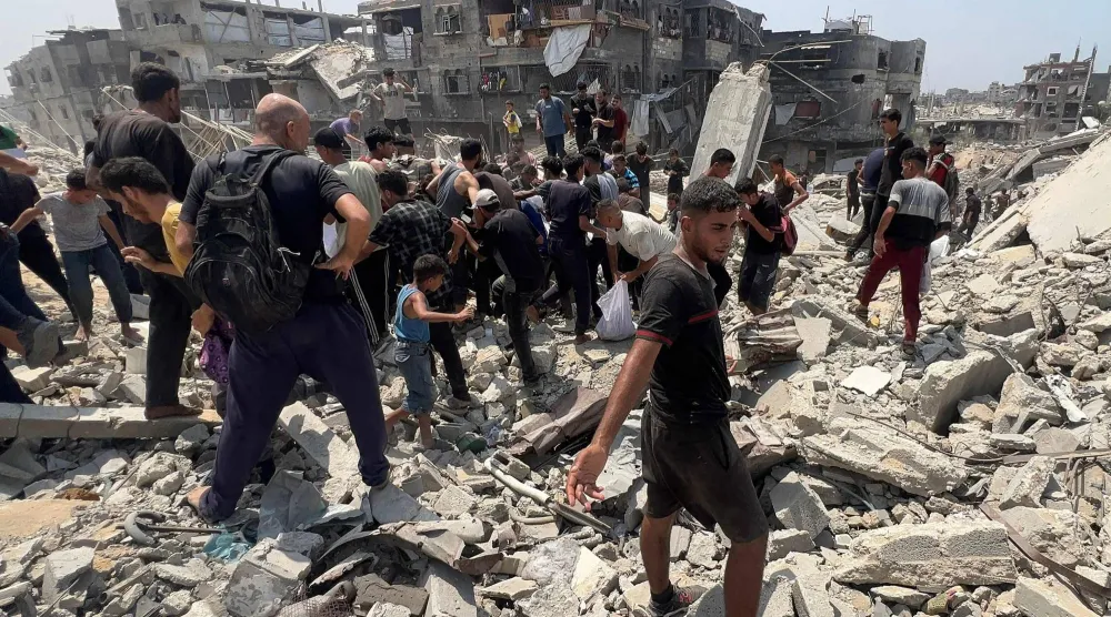 فلسطينيون يتدافعون حول طرد إنساني أسقطته طائرة عسكرية في جباليا بشمال قطاع غزة (أ.ف.ب)